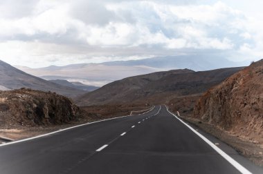 Betancuria Massif, Fuerteventura, Kanarya Adaları, İspanya 'nın renkli uzak bazal tepeleri ve dağları üzerindeki dağ asfalt yolu.