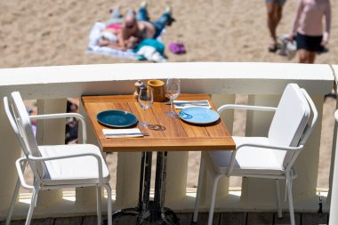 Öğle yemeğinden önce, güneşli Biarritz, Bask Ülkesi, Fransa 'da masaları servis edilen boş şık bir plaj kafe.