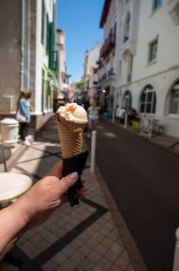 Elinde vanilyalı meyve vejetaryen dondurması olan bir kadın Biarritz, Fransa 'da caddede waffle külahında.