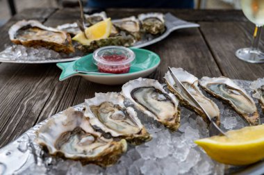 Güneşli bir günde, Arcachon Bassin, Gujan-Mestras limanı, Bordeaux, Fransa 'da, istiridye sayısı 0 olan istiridye çiftçilik köyündeki açık hava kafesinde taze canlı istiridye ve ekmek yemek..