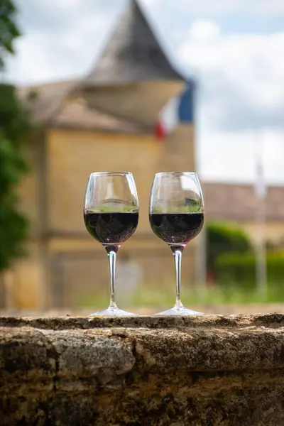 stock image Glasses of french dry red wine in old wine domain on Graves vineyards in Portets village and old wine making castle on background, Bordeaux, France