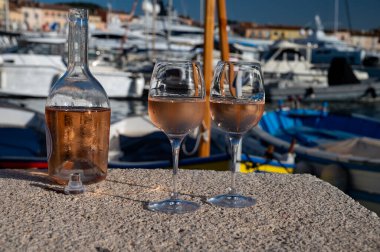 Saint-Tropez 'de eski balıkçı tekneleri limanı ve yat limanında soğuk Fransız gülü Cote de Provence şarabı, Fransa' nın Provence şehrinde yaz tatili