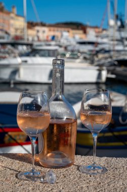 Saint-Tropez 'de eski balıkçı tekneleri limanı ve yat limanında soğuk Fransız gülü Cote de Provence şarabı, Fransa' nın Provence şehrinde yaz tatili