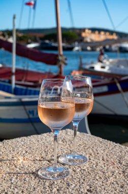 Saint-Tropez 'de eski balıkçı tekneleri limanı ve yat limanında soğuk Fransız gülü Cote de Provence şarabı, Fransa' nın Provence şehrinde yaz tatili