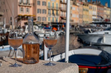 Saint-Tropez 'de eski balıkçı tekneleri limanı ve yat limanında soğuk Fransız gülü Cote de Provence şarabı, Fransa' nın Provence şehrinde yaz tatili