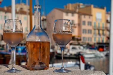 Saint-Tropez 'de eski balıkçı tekneleri limanı ve yat limanında soğuk Fransız gülü Cote de Provence şarabı, Fransa' nın Provence şehrinde yaz tatili