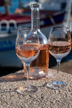 Saint-Tropez 'de eski balıkçı tekneleri limanı ve yat limanında soğuk Fransız gülü Cote de Provence şarabı, Fransa' nın Provence şehrinde yaz tatili