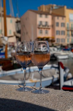 Saint-Tropez 'de eski balıkçı tekneleri limanı ve yat limanında soğuk Fransız gülü Cote de Provence şarabı, Fransa' nın Provence şehrinde yaz tatili