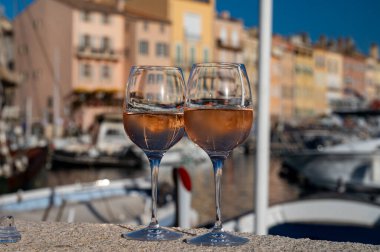 Saint-Tropez 'de eski balıkçı tekneleri limanı ve yat limanında soğuk Fransız gülü Cote de Provence şarabı, Fransa' nın Provence şehrinde yaz tatili