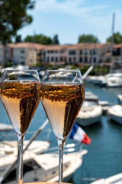 French brut rose champagne sparkling wine in tulip glasses in yacht harbour of Port Grimaud near Saint-Tropez, French Riviera vacation, Var, France is summer clipart