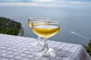 Soğuk, köpüklü şarap, kava ya da şampanya. Deniz manzaralı iki coupe bardakta.