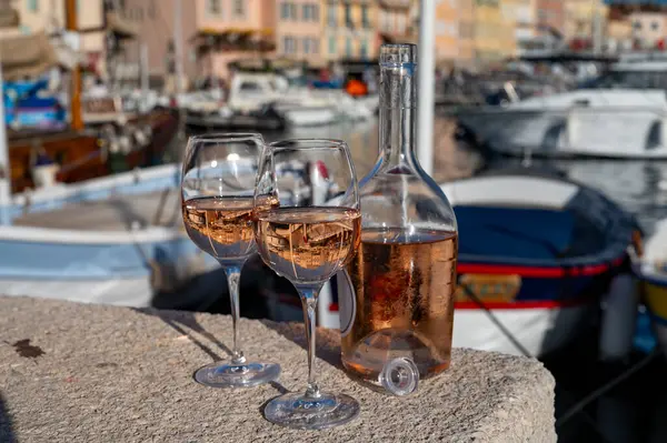 Saint-Tropez 'de eski balıkçı tekneleri limanı ve yat limanında soğuk Fransız gülü Cote de Provence şarabı, Fransa' nın Provence şehrinde yaz tatili