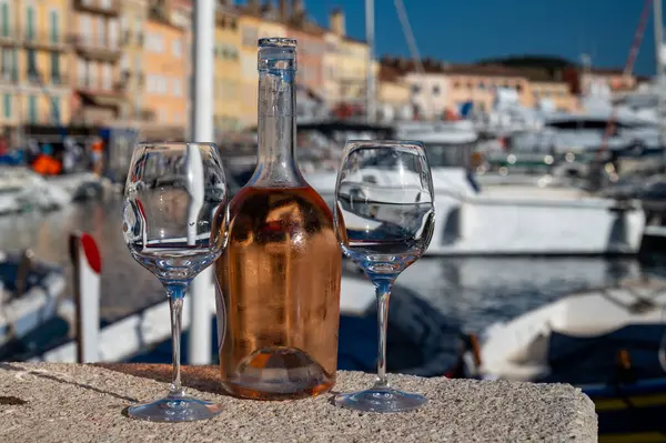 Saint-Tropez 'de eski balıkçı tekneleri limanı ve yat limanında soğuk Fransız gülü Cote de Provence şarabı, Fransa' nın Provence şehrinde yaz tatili