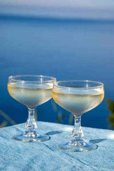 stock image Cold sparkling wine, cava or champagne in two coupe glasses on table with blue sea view