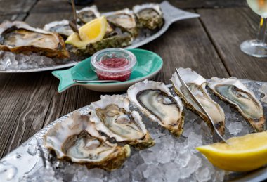 Güneşli bir günde, Arcachon Bassin, Gujan-Mestras limanı, Bordeaux, Fransa 'da, istiridye sayısı 0 olan istiridye çiftçilik köyündeki açık hava kafesinde taze canlı istiridye ve ekmek yemek..