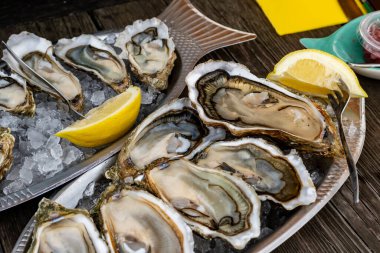 Fransa 'nın Gujan-Mestras limanındaki Arcachon körfezi istiridye çiftliği köyündeki restoranda taze çiğ istiridye, deniz kabuğu, liman, ekmek, tereyağı ve beyaz şarapla servis edilen tabaklar.