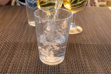 Garson cam şişeden maden suyunu bardağa dolduruyor, yiyecek konsepti, kapat.