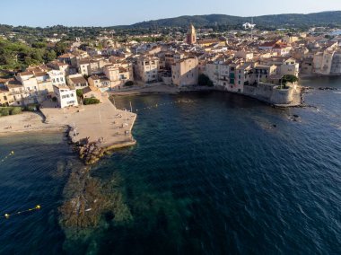 Aerial view on bays, beaches, old colorful houses of famous Saint-Tropez town on French Riviera at sunset, Var, Provence, France, summer vacation destination clipart