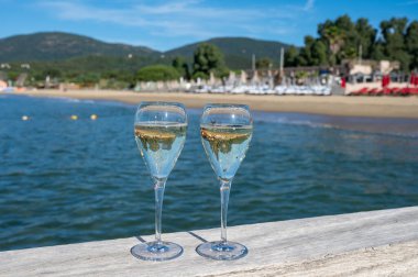 Summer time in Provence, two glasses of cold champagne cremant sparkling wine on famous Pampelonne white sandy beach near Saint-Tropez in sunny day, Var department, France, beach club party clipart