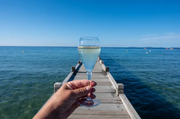 stock image Summer time in Provence, hand with glass of cold champagne cremant sparkling wine on famous Pampelonne white sandy beach near Saint-Tropez in sunny day, Var department, France, beach club party