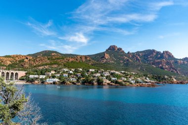 Corniche d ya da Corniche de lEsterel güzel kıyı yolu, kristal mavi deniz ve gökyüzü Massif de IEsterel dağlarının kırmızımsı rengiyle birleşmiş Fransa 'da seyahat varış noktası