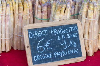 Souillac, Dordogne, Fransa 'daki yerel çiftçi pazarında satılık taze çiğ, pembe kuşkonmaz sebzeleri. İngilizce çeviri: Payrignac 'ta yerel üretilen 1 kg deste