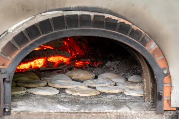 stock image Baking of flat pita bread in wood-fired oven on local street market