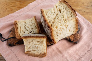 Taze pişmiş büyük ekşi mayalı geleneksel İtalyan buğday ekmeği zeytin ağacının üzerinde parça parça yanmış fırın.