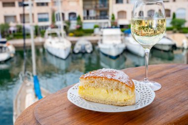 Fransız Rivierası 'nın şarap ve kekleri, bir bardak soğuk beyaz Cote de Provence şarabı ve Port Grimaud limanında Tarte Tropezienne keki, Fransa' nın Provence şehrinde yaz tatili