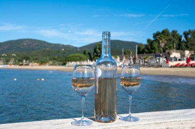 Provence 'den bir şişe soğuk gül şarabı ve beyaz kumlu plaj plajı Plage de Pampelonne, Saint-Tropez yakınlarında, Fransa' da yaz tatili, sahil kulübü partisi.