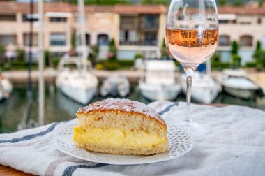 Fransız Riviera şarabı, bir bardak soğuk gül Cote de Provence şarabı ve Port Grimaud 'un yat limanında Tarte Tropezienne keki, Fransa' nın Provence şehrinde yaz tatili