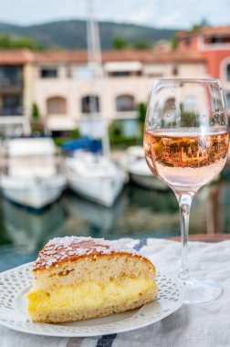Fransız Riviera şarabı, bir bardak soğuk gül Cote de Provence şarabı ve Port Grimaud 'un yat limanında Tarte Tropezienne keki, Fransa' nın Provence şehrinde yaz tatili