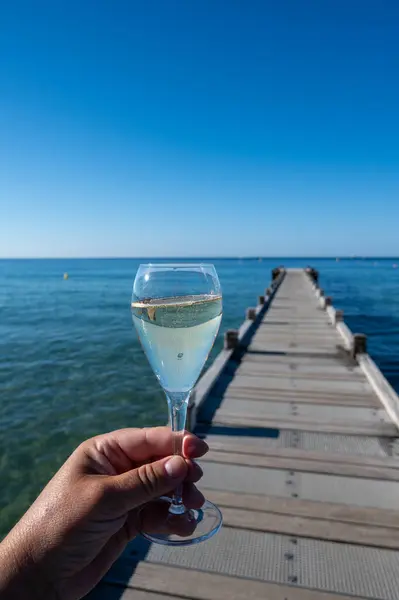 stock image Summer time in Provence, hand with glass of cold champagne cremant sparkling wine on famous Pampelonne white sandy beach near Saint-Tropez in sunny day, Var department, France, beach club party