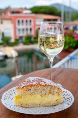 Fransız Rivierası 'nın şarap ve kekleri, bir bardak soğuk beyaz Cote de Provence şarabı ve Port Grimaud limanında Tarte Tropezienne keki, Fransa' nın Provence şehrinde yaz tatili