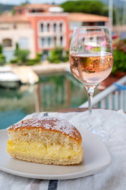 Fransız Riviera şarabı, bir bardak soğuk gül Cote de Provence şarabı ve Port Grimaud 'un yat limanında Tarte Tropezienne keki, Fransa' nın Provence şehrinde yaz tatili