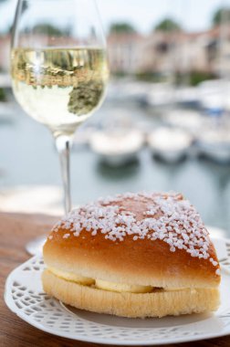 Fransız Rivierası 'nın şarap ve kekleri, bir bardak soğuk beyaz Cote de Provence şarabı ve Port Grimaud limanında Tarte Tropezienne keki, Fransa' nın Provence şehrinde yaz tatili