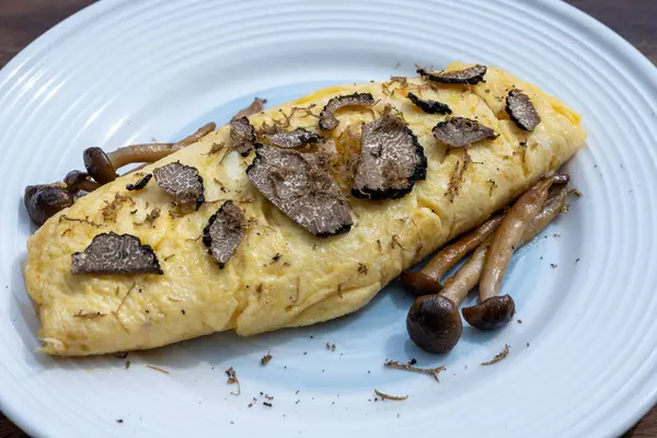 stock image French omelette with mushrooms, fresh farmers chicken eggs and black summer truffle mushroom in pieces for making truffle dishes with tasty aroma