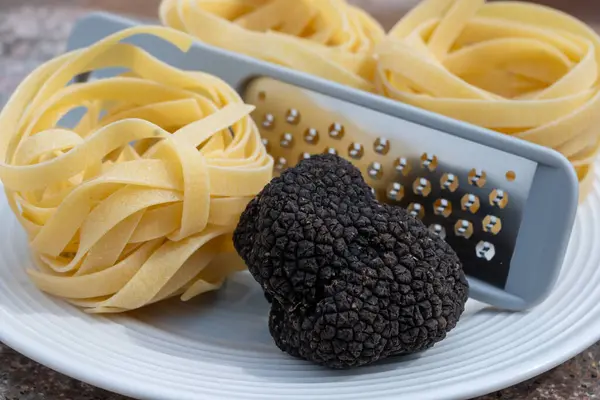 stock image Italian food, tagliatelle pasta with  mushrooms, fresh black summer truffle mushroom for making truffle dishes with tasty aroma, vegetarian dinner