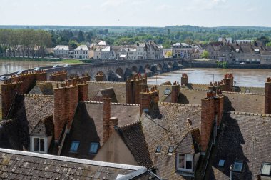 Views of old part of town of Gien on the Loire river, in Loiret department, France, houses with tiled roofs and chimneys, river and bridge clipart