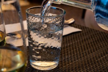 Garson cam şişeden maden suyunu bardağa dolduruyor, yiyecek konsepti, kapat.