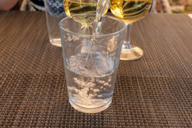 Garson cam şişeden maden suyunu bardağa dolduruyor, yiyecek konsepti, kapat.