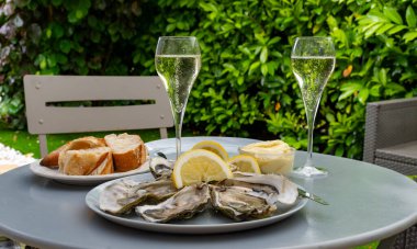 Şampanya kadehli köpüklü şarap ve Gujan-Mestras 'taki istiridye çiftliğinde servis edilen Arcachon körfezinden istiridye yumuşakçaları limon, baquette ekmeği ve tereyağlı.