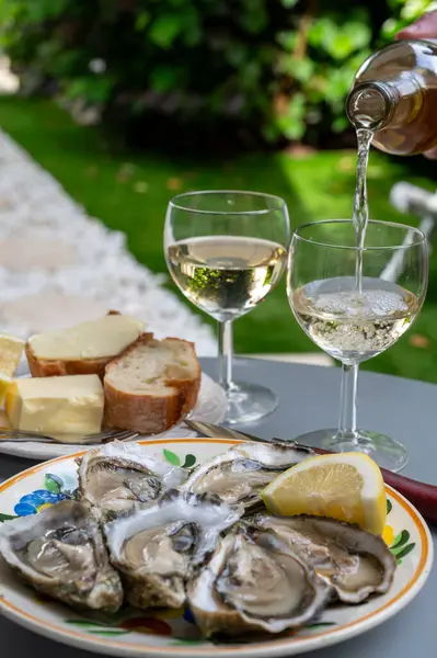 stock image Plate with fresh live raw oysters seashells with citron, bread, butter and white wine served at restaurant in oyster-farming village, Arcachon bay, Gujan-Mestras port, France