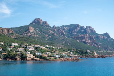 Corniche d ya da Corniche de lEsterel güzel kıyı yolu, kristal mavi deniz ve gökyüzü Massif de IEsterel dağlarının kırmızımsı rengiyle birleşmiş Fransa 'da seyahat varış noktası
