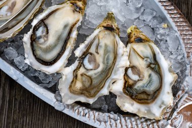 Plate with fresh live raw oysters seashells with citron, bread, butter and white wine served on ice at restaurant in oyster-farming village, Arcachon bay, Gujan-Mestras port, France clipart