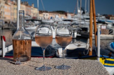 Saint-Tropez 'de eski balıkçı tekneleri limanı ve yat limanında soğuk Fransız gülü Cote de Provence şarabı, Fransa' nın Provence şehrinde yaz tatili