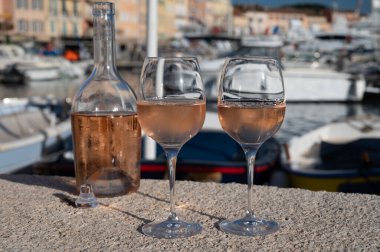 Saint-Tropez 'de eski balıkçı tekneleri limanı ve yat limanında soğuk Fransız gülü Cote de Provence şarabı, Fransa' nın Provence şehrinde yaz tatili