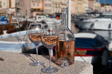 Saint-Tropez 'de eski balıkçı tekneleri limanı ve yat limanında soğuk Fransız gülü Cote de Provence şarabı, Fransa' nın Provence şehrinde yaz tatili