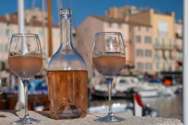 Saint-Tropez 'de eski balıkçı tekneleri limanı ve yat limanında soğuk Fransız gülü Cote de Provence şarabı, Fransa' nın Provence şehrinde yaz tatili