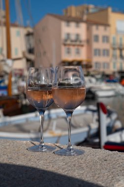Saint-Tropez 'de eski balıkçı tekneleri limanı ve yat limanında soğuk Fransız gülü Cote de Provence şarabı, Fransa' nın Provence şehrinde yaz tatili
